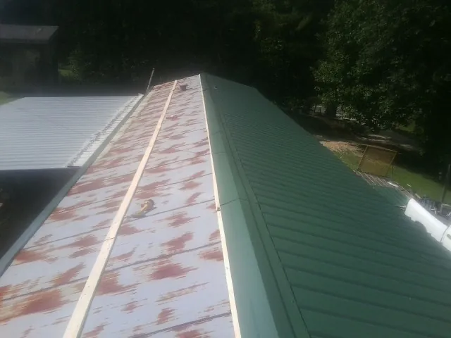 Old rusted panels beside newly installed green metal roofing — Wind Damage Roof Repair by Roofing Brothers in Berkshire