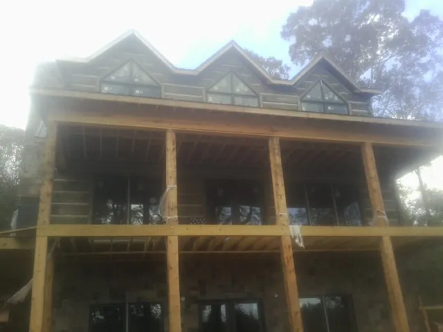 Dormers and porch framing on a large log home under construction — Roof Coating work by our crew in Berkshire