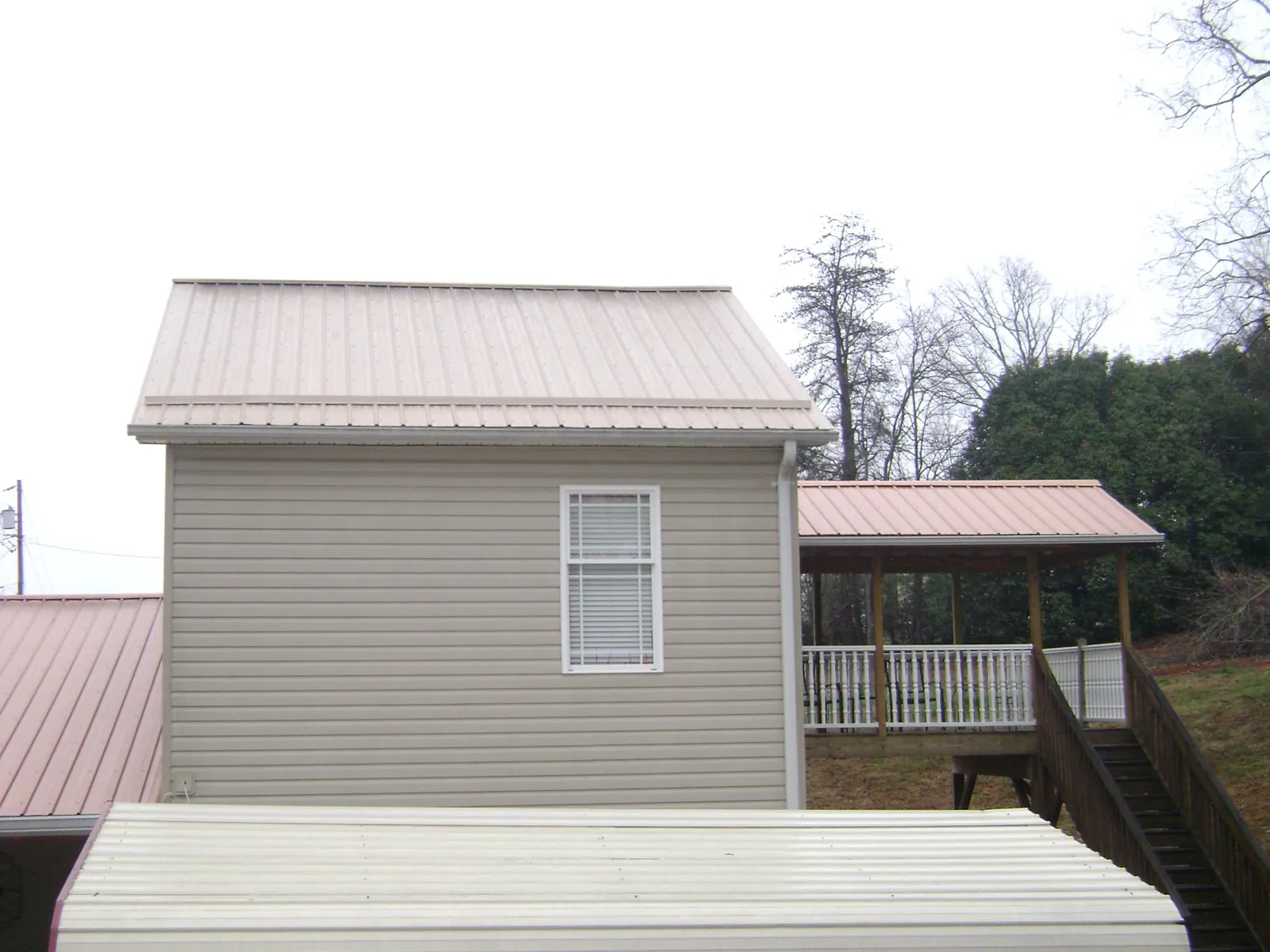 Tan metal roofs on a two story addition and attached porch, from a Roof Replacement job in Berkshire